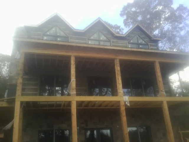 Dormers and porch framing on a large log home under construction — Roof Coating work by our crew in Roosevelt