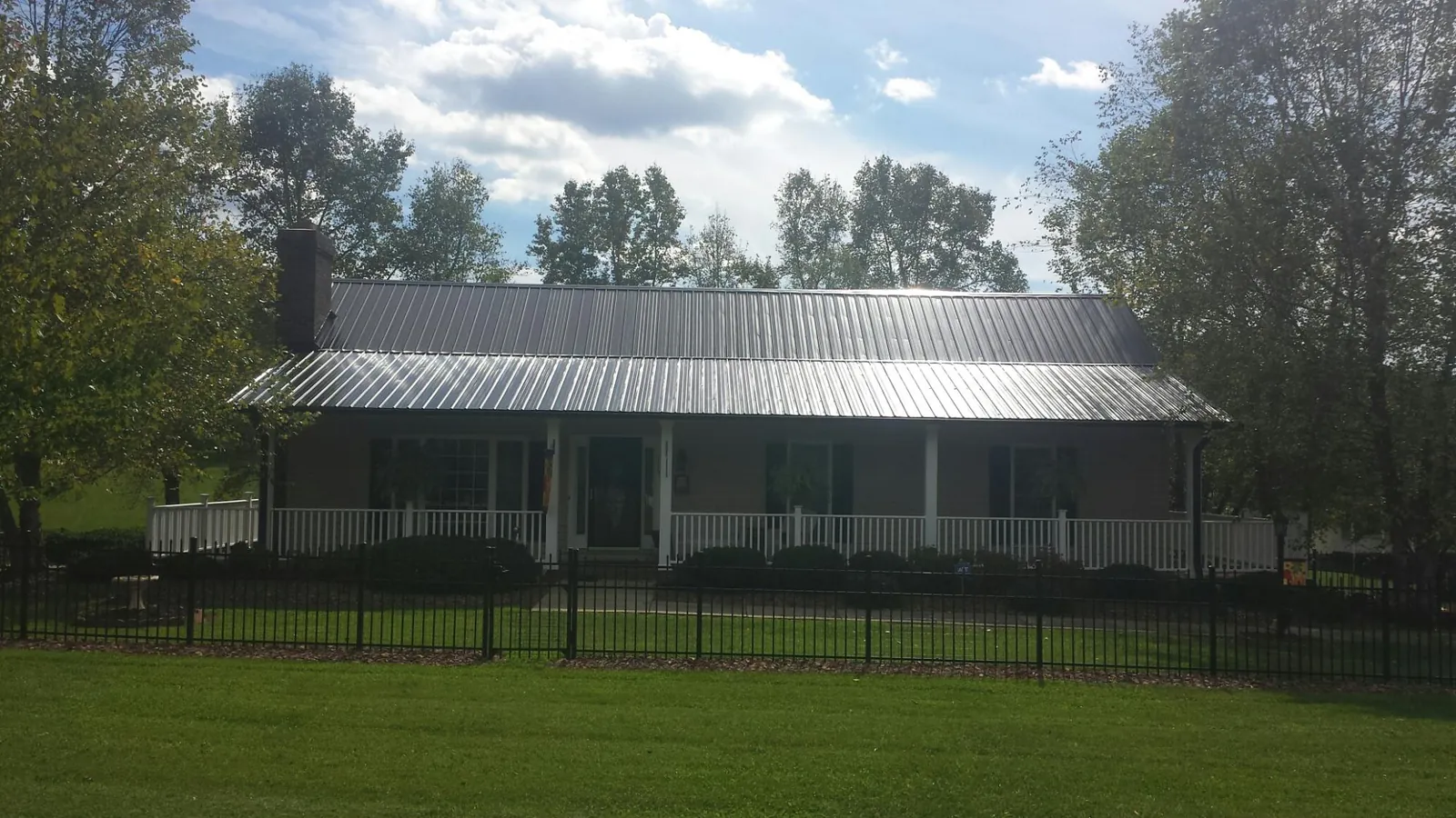 Gray metal roof on a brick ranch with a full width front porch — Gutter Guard Installation work by our crew in Roosevelt